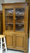 ANTIQUE LIGHT OAK STANDING CORNER CUPBOARD with two door glazed top, arch decoration and two door c