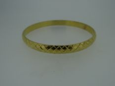 YELLOW METAL LADIES BANGLE OF CRISS-CROSS DESIGN (tested as high carat approximately 22ct gold),