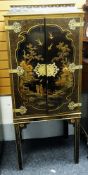 20TH CENTURY JAPANNED CABINET, two doors centred with large village scene with figures, decorative