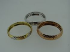 THREE GOLD BANDS, one rose gold, one yellow, white and rose, and one white gold, all stamped '9k',