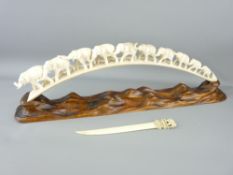 AN INDIAN CARVED TUSK ELEPHANT TRAIN, 49cms length on a polished natural wood stand and an