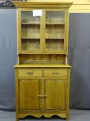 AN EDWARDIAN STRIPPED PINE BOOKCASE CUPBOARD, twin upper section glazed doors over a two drawer with
