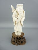 AN IVORY FIGURINE OF AN OLD ORIENTAL SAGE carrying a sword on his back on a carved wooden base,