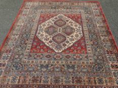 EASTERN STYLE WOVEN WOOLLEN CARPET, red ground and multi bordered with central repeat diamond