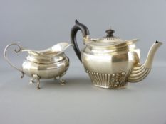 SILVER TEAPOT & MILK JUG - a teapot of oblong angled form with scrolled decoration to the base,
