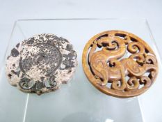 TWO CHINESE CARVED JADE ROUNDELS, one showing a mythical beast, 6.75cms diameter, the other having a