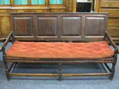 ANTIQUE OAK OPEN HALL BENCH, the back having four chamfered panels and shaped arms on turned front