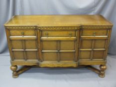 CIRCA 1920 OAK BREAK-FRONT SIDEBOARD with carved frieze detail over three drawers and cupboard