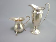 TWO SILVER CREAM JUGS - (1) tall, tapered with panelled decoration and long handle to circular base,