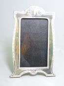 SILVER EASEL PICTURE FRAME, shaped and with dart and ribbon decoration in classical style,