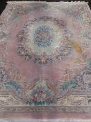 CHINESE WASHED WOOLEN CARPET, pink and cream ground with floral pattern centre and tasselled ends,