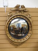 A REGENCY STYLE GILT CONVEX WALL MIRROR with eagle cresting and bobble detail, (some restoration