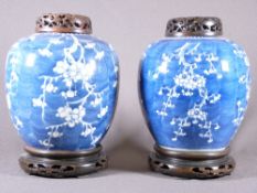 PRUNUS BLOSSOM COVERED JARS - a near pair with hardwood stands and lids, twin concentric rings to