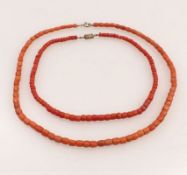 Zwei Korallencolliers20. Jh.Umlaufend polierte tonneauförmige Glieder, Kastenschloss und