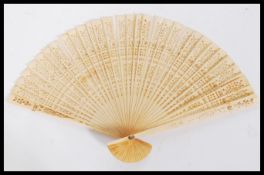 An early 20th Century ivory fan having 32 pierced decoration panels / blades attached by a ribbon.