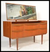 A vintage retro 20th Century teak dressing table chest of drawers raised on tapering legs. the