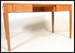A mid century golden oak Utility desk being raised on squared legs with a bank of drawers underneath