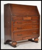 A 1940's Art Deco oak bureau being raised on ball feet with a bank of drawer under bureau atop