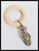 An early 20th Century teething ring with a silver teddy bear figure attached. Silver lion mark to