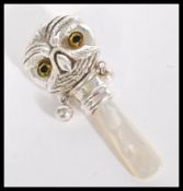 A silver babies / childs rattle in the form of an owl with yellow and black glass eyes having a