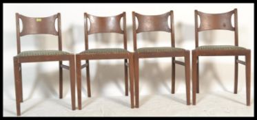 A set of 4 mid century teak wood ' butterfly ' back dining chairs being raised on square tapering