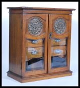 An early 20th Century Edwardian Art Nouveau table top oak smokers cabinet having twin glazed doors