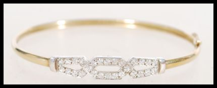 A stamped 9ct yellow gold bangle bracelet having a white gold section of crossover design set with