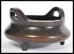 A 19th Century Chinese bronze censer ding bowl raised on tripod stubb feet with hoop handles. Four