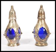 A pair of 20th Century silver plated condiments of bulbous form having pierced sides with blue glass