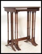 An Edwardian mahogany nest of tables being raised on ring turned legs in the form of bamboo set on