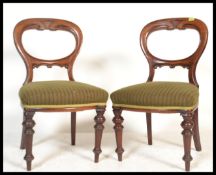 A pair of Victorian mahogany balloon back dining chairs being raised on turned legs with green