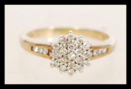 A hallmarked 9ct gold diamond cluster ring having a central flower head with diamond encrusted