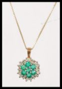 A hallmarked 9ct gold emerald and diamond cluster pendant necklace. Chain measures 18 inches,