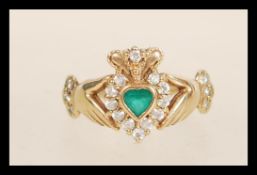 A hallmarked 9ct gold Claddagh ring set with a central green stone with white stone accents.