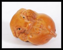 A 20th century Japanese carved wooden netsuke in the form of a bison with signature present.