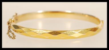 A 9ct gold B-Core bracelet bangle having diamond cut decoration with clip clasp and safety chain.