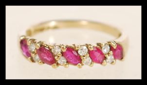 A hallmarked 9ct gold ruby and diamond ring set with alternating marquise cut rubies and round cut