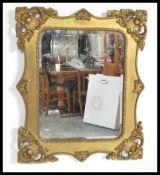 An early 20th century gilt wall mirror of rectangular form having heavy rococo insipiration to
