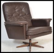 A vintage 1960's / 70's retro Danish swivel armchair upholstered with brown leather, button backed