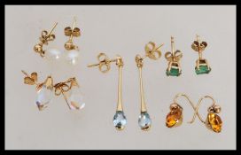 A group of 9ct gold earrings to include green stone studs, crystal drops, light blue stone drops,