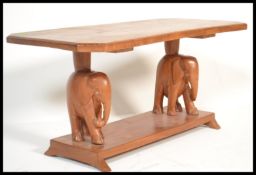 An early 20th century hardwood coffee table of rectangular form being raised on elephant carved