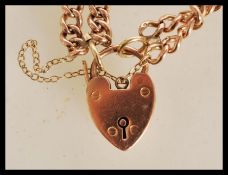 A hallmarked 9ct gold heart lock bracelet with a double curb link chain. Hallmarked Birmingham