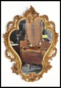 A 20th century armorial rococo shaped antique style gilt rococo wall mirror. The decorative frame