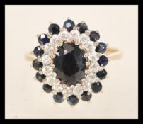 A hallmarked 9ct gold ring set with a an oval cut blue sapphire within a halo of white and stones