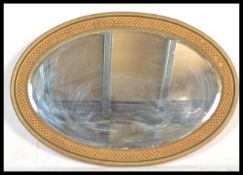 An early 20th Century Edwardian oval wall mirror having bevelled glass having a moulded frame with