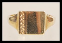 A hallmarked 9ct gold signet ring having a square head with a pattern engraved to one side.