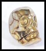 A vintage 20th century brass vesta case in the form of a skull having hinged jaw lid. Measures 4cm
