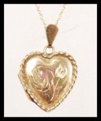 A hallmarked 9ct gold pendant necklace having a heart shaped pendant locket with floral engraving to