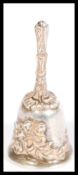 An early 20th Century silver hallmarked miniature bell having embossed flowers to the sides and
