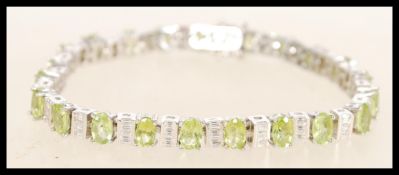 A sterling silver CZ and peridot line bracelet having alternating faceted peridots with square cut